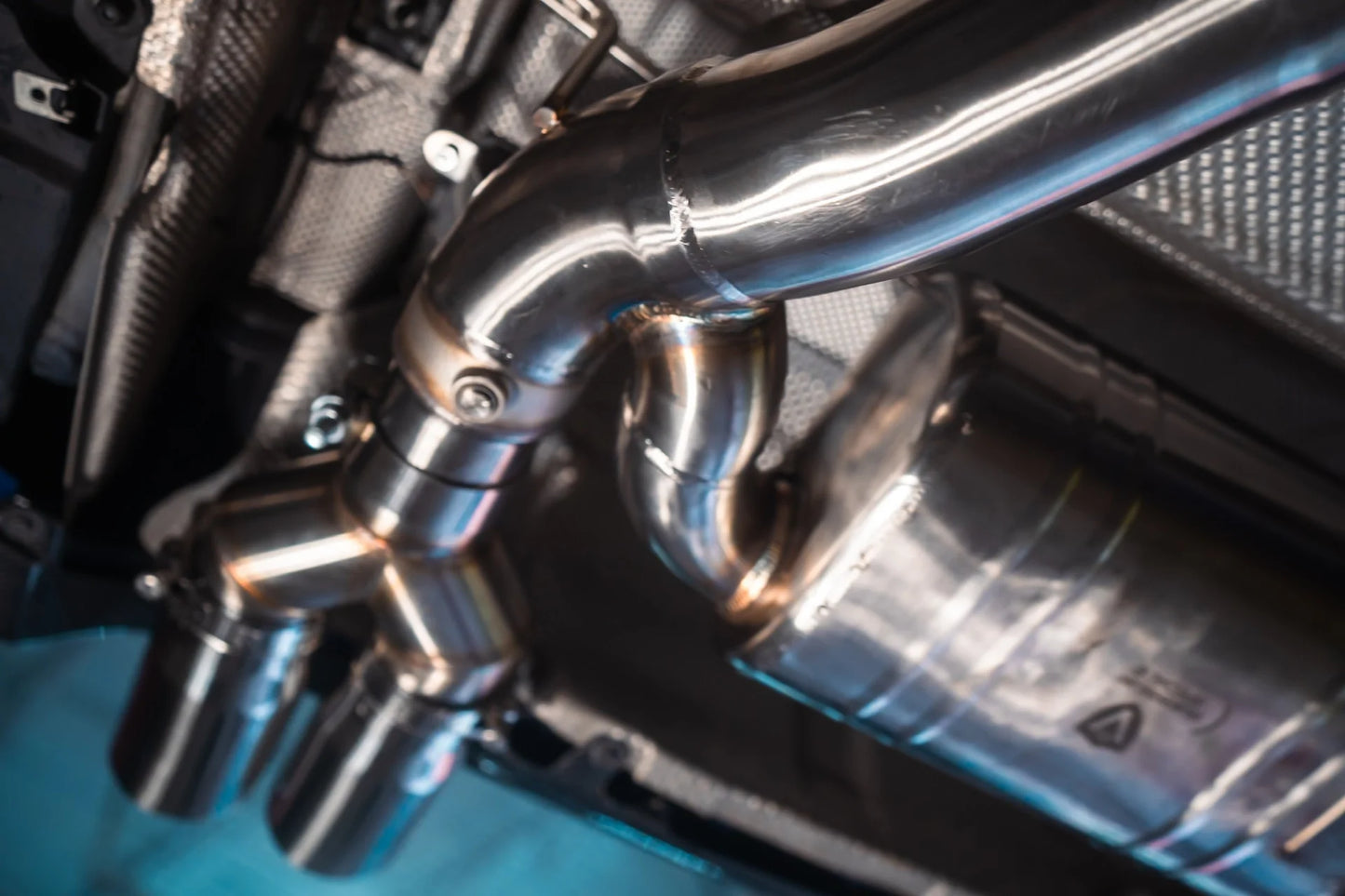 View of the tips from under a car for the Valvetronic BMW F8x M3 / M4 Equal Length Valved Sport Exhaust System | Insignist Motorsports